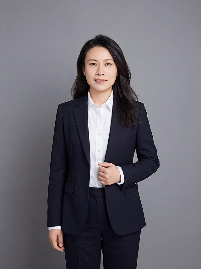 参考图中保留人物脸型、发型、年龄等特征生成金融律师职场形象照，标准焦段50mm,f/4光圈，平视视角，镜头与人物视线齐平；人物占画面70%，人物居中，居中构图，位于画面中心，为视觉聚焦点，入境范围头部及以下至臀部下方10cm，半身像；左右留少量背景空间；头部与画面顶部保留5%空间；头部发型完整，头肩比例协调，人物结构准确；发质微微柔顺，微微蓬松。身穿藏青黑色精纺羊毛混纺西装外套，平驳领设计，面料呈细腻微微哑光质感；内搭白色高支精梳棉衬衫；下装藏青黑色精纺羊毛混纺九分西装裤；着装正式干练；严谨理性、逻辑清晰、不怒自威、公信力强；身形匀称，姿态端正，身体挺拔。呈站姿，右手轻握西装前襟的自然姿态，肢体放松且自信；去除所有配饰，简约微微中性灰色纯色背景，呈现均匀柔和质感，背景光线均匀柔和，强化色彩对比的高级感，极简干净；画质超高分辨率、细节清晰，现代精致感风格；肤质精细化处理；眼神直视镜头，目光坚定且澄澈，表情自然，嘴角上扬；清透自然裸妆，轻薄底妆+淡唇妆，妆感轻薄轻透裸肌感，通透感肤质，肤质自然细腻，肤色健康均匀，雾面柔光裸肌感，保留真实皮肤细节，正面柔光补光，4800K中性光，面部光比1:1.5，色调明亮，中近景写实摄影，对焦清晰，高清保留皮肤细节；分辨率4K，去除人物之外的所有元素，严格按照图片内容生成，画面比例3:4
