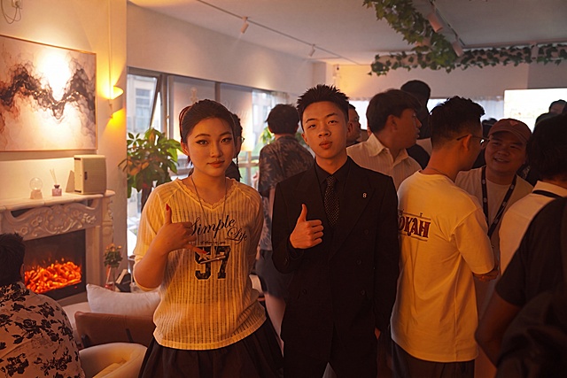 使用相同方法精修图中人物：提升面部精致度（皮肤细腻、眼神光自然、轮廓清晰），增强光影层次与肤色通透感，保持真实写实风格；重点突出前景两位人物，背景人群适度虚化以强化主体氛围，保留原场景暖色调与构图