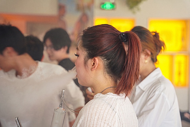 仅进行极轻微的画质增强：提升前景女性面部与发丝细节清晰度、皮肤质感与光影层次，保持真实写实风格；严格不改变发型（包括发色、马尾、发圈位置）、服饰、姿态、背景人物虚化程度、灯光氛围及构图——所有元素位置、形态、比例均与原图一致