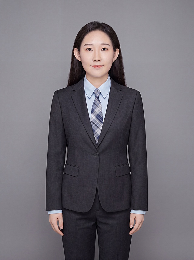 参考图中保留人物脸型、发型、年龄等特征生成职场形象照，标准焦段50mm，f/4光圈，平视视角，镜头与人物视线齐平；人物占画面合适比例，人物居中，居中构图，位于画面中心，为视觉聚焦点，全身照，展现人物完整身形；左右留少量背景空间；头部与画面顶部保留合理空间；头部发型完整，头身比例协调，人物结构准确；身穿深色精纺羊毛混纺西装外套，平驳领设计，面料呈细腻微微哑光质感；内搭浅色高支精梳棉衬衫；下装深色精纺羊毛混纺西装裤；着装正式干练；专业稳重；身形匀称，姿态端正，身体挺拔。呈站姿，双手自然下垂的自然姿态，肢体放松且自信；发质微微柔顺，微微蓬松，保留原有格纹领带配饰；简约微微中度灰色纯色背景，呈现均匀柔和质感，背景光线均匀柔和，强化色彩对比的高级感，极简干净；画质超高分辨率、细节清晰，现代精致感风格；肤质精细化处理；眼神直视镜头，目光坚定且澄澈，表情自然，嘴角上扬；清透自然裸妆，轻薄底妆+淡唇妆，妆感轻薄轻透裸肌感，通透感肤质，肤质自然细腻，肤色健康均匀，雾面柔光裸肌感，保留真实皮肤细节｡正面柔光补光，4800K中性光，面部光比1:1.5，色调明亮｡写实摄影，对焦清晰，高清保留皮肤细节；分辨率4K，去除人物之外的所有元素，严格按照图片内容生成，画面比例3:4