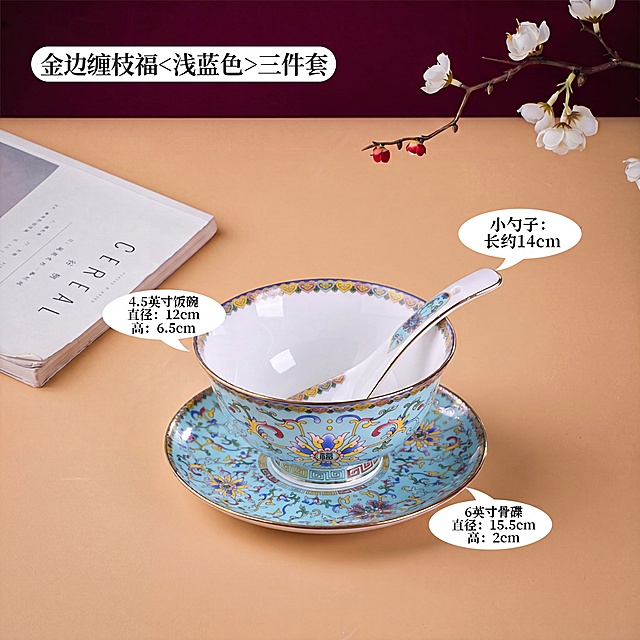 保留原图整体场景：浅驼色桌面、酒红色背景、左侧书本、右侧花枝，保留原有的尺寸标注文字，只把原黄色三件套产品替换为图二这款浅蓝色珐琅彩缠枝福三件套（碗、碟、勺），保持位置、光影和整体风格一致，标题改为金边缠枝福<浅蓝色>三件套