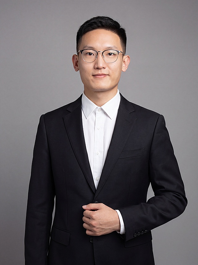 参考图中保留人物脸型、发型、年龄等特征生成职场形象照,标准焦段50mm,f/4光圈(f/2.8-f/4区间),平视视角(镜头与人物视线齐平);人物占画面70%,人物居中(居中构图),位于画面中心,为视觉聚焦点,入境范围头部及以下至臀部下方10cm(半身像);左右留少量背景空间;头部与画面顶部保留5%空间;头部发型完整,头肩比例协调,人物结构准确;发质微微柔顺，微微蓬松。身穿深黑色精纺羊毛混纺西装外套,(平驳领设计,面料呈细腻微微哑光质感);内搭白色高支精梳棉衬衫;下装深黑色精纺羊毛混纺西裤;着装正式干练;专业稳重;身形匀称,姿态端正,身体挺拔。呈站姿，右手轻握西装前襟，肢体放松且自信;佩戴眼镜;简约中性灰纯色背景(呈现均匀柔和质感),背景光线均匀柔和,强化色彩对比的高级感。极简干净;画质超高分辨率、细节清晰,现代精致感风格;肤质精细化处理;眼神直视镜头,目光坚定且澄澈,表情自然。嘴角上扬;肤质自然细腻,肤色健康均匀,皮肤状态清爽干净,保留真实皮肤细节｡正面柔光补光,4800K中性光,面部光比1:1.5｡中近景写实摄影,对焦清晰,面部雾面柔光,轻透裸肌感,高清保留皮肤细节｡分辨率4K,去除人物之外的所有元素。严格按照图片内容生成。画面比例3:4
