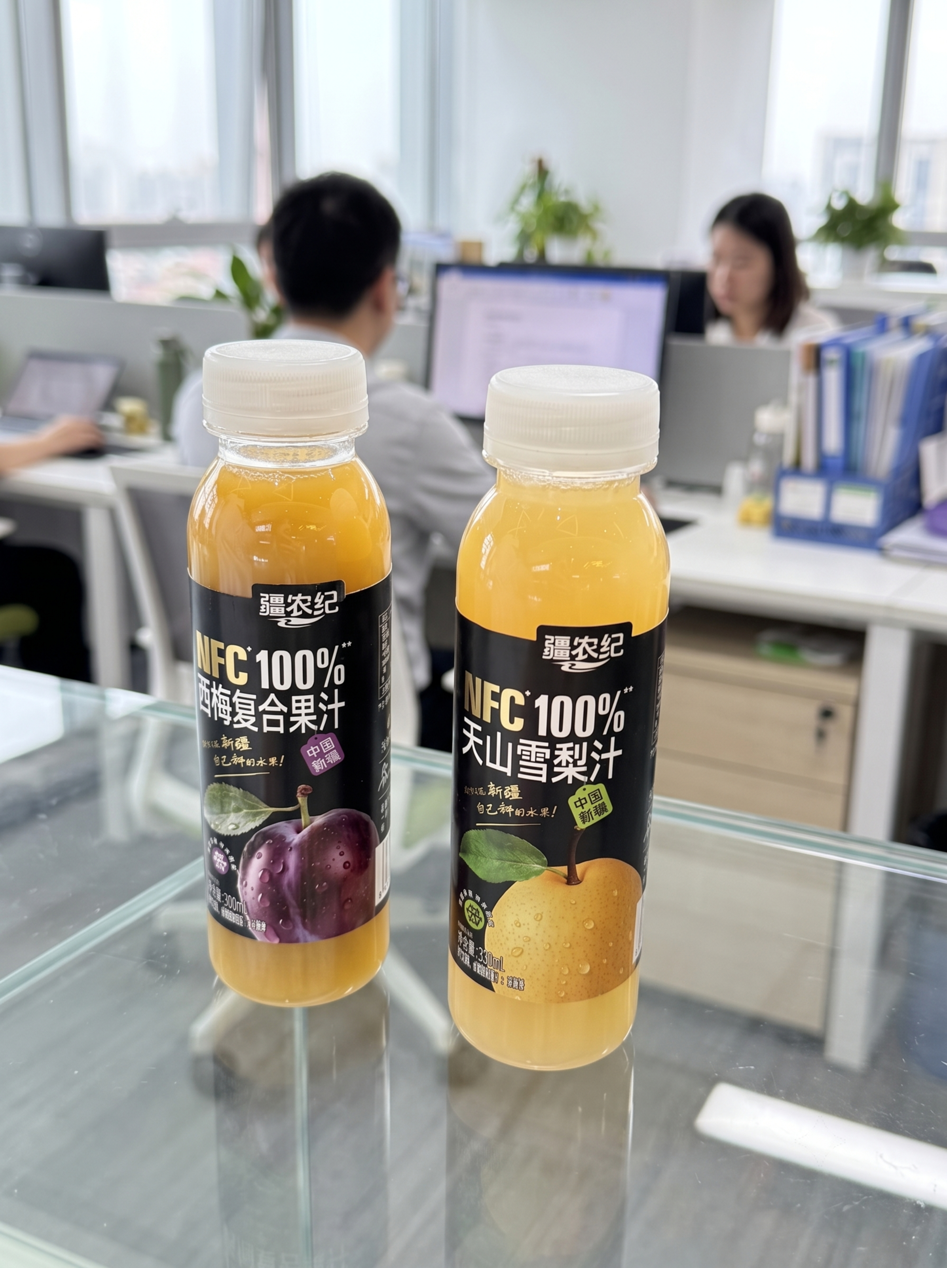 保留两瓶果汁在玻璃柜摆放构图，替换背景为开放式办公区员工办公背… - 图片创意预览