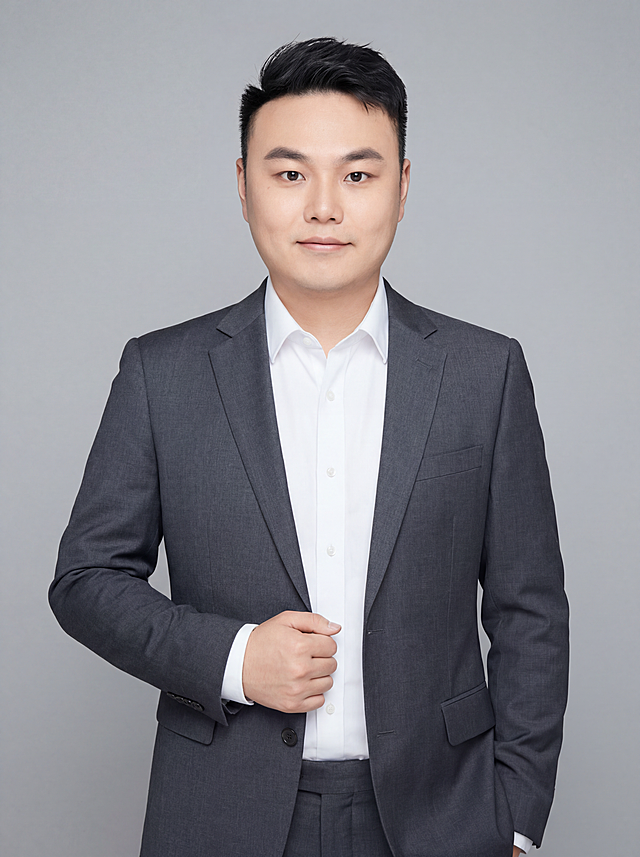 参考图中保留人物脸型、发型、年龄等特征生成职场形象照,标准焦段50mm,f/4光圈(f/2.8-f/4区间),平视视角(镜头与人物视线齐平);人物占画面70%,人物居中(居中构图),位于画面中心,为视觉聚焦点,入境范围头部及以下至臀部下方10cm(半身像);左右留少量背景空间;头部与画面顶部保留5%空间;头部发型完整,头肩比例协调,人物结构准确;发质微微柔顺，微微蓬松。身穿深灰色精纺羊毛混纺西装外套,(平驳领设计,面料呈细腻微微哑光质感);内搭白色高支精梳棉衬衫;下装深灰色精纺羊毛混纺西裤;着装正式干练;专业稳重;身形匀称,姿态端正,身体挺拔。呈自然站姿，右手轻握西装前襟，肢体放松且自信;去除原图右上角和左下角所有装饰元素；简约微微中性灰色纯色背景(呈现均匀柔和质感),背景光线均匀柔和,强化色彩对比的高级感，极简干净;画质超高分辨率、细节清晰,现代精致感风格;肤质精细化处理;眼神直视镜头,目光坚定且澄澈,表情自然。嘴角上扬;肤质自然细腻,肤色健康均匀,皮肤状态清爽干净,保留真实皮肤细节｡正面柔光补光,4800K中性光,面部光比1:1.5｡中近景写实摄影,对焦清晰,面部雾面柔光,轻透裸肌感,高清保留皮肤细节｡分辨率4K,去除人物之外的所有装饰元素。严格按照参考图片内容生成，画面比例3:4