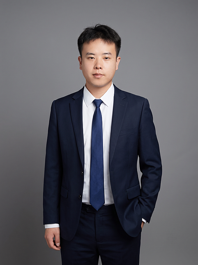 参考图中保留人物脸型、发型、年龄等特征生成职场形象照，标准焦段50mm，f/4光圈，平视视角。人物占画面70%，居中构图，位于画面中心，为视觉聚焦点，入境范围头部及以下至臀部下方10cm，左右留少量背景空间，头部与画面顶部保留5%空间，头部发型完整，头肩比例协调，人物结构准确。发质微微柔顺，微微蓬松。身穿藏青色精纺羊毛混纺西装外套，平驳领设计，面料呈细腻微微哑光质感；内搭白色高支精梳棉衬衫；下装藏青色精纺羊毛混纺西裤；搭配深蓝色领带；着装正式干练，专业稳重，身形匀称，姿态端正，身体挺拔。呈自然站姿，左手插兜，肢体放松且自信。简约微微中度灰色纯色背景，呈现均匀柔和质感，背景光线均匀柔和，强化色彩对比的高级感，极简干净。画质超高分辨率、细节清晰，现代精致感风格；肤质精细化处理；眼神直视镜头，目光坚定且澄澈，表情自然。分辨率4K，去除人物之外的所有元素，严格按照图片内容生成。肤质自然细腻，肤色健康均匀，皮肤状态清爽干净，保留真实皮肤细节。正面柔光补光，4800K中性光，面部光比1:1.5。中近景写实摄影，对焦清晰，面部雾面柔光，轻透裸肌感，高清保留皮肤细节。画面比例3:4