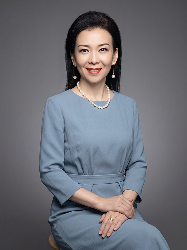参考图重新生成，保留原人物长相五官特征不变，半身形象照，摄影棚级，干净中性灰色纯色背景，穿搭雾霾蓝色收腰连衣裙，自然坐姿，自然真实质感，不改变人物五官长相，专业打光，高清画质，半身形象照，分辨率4K