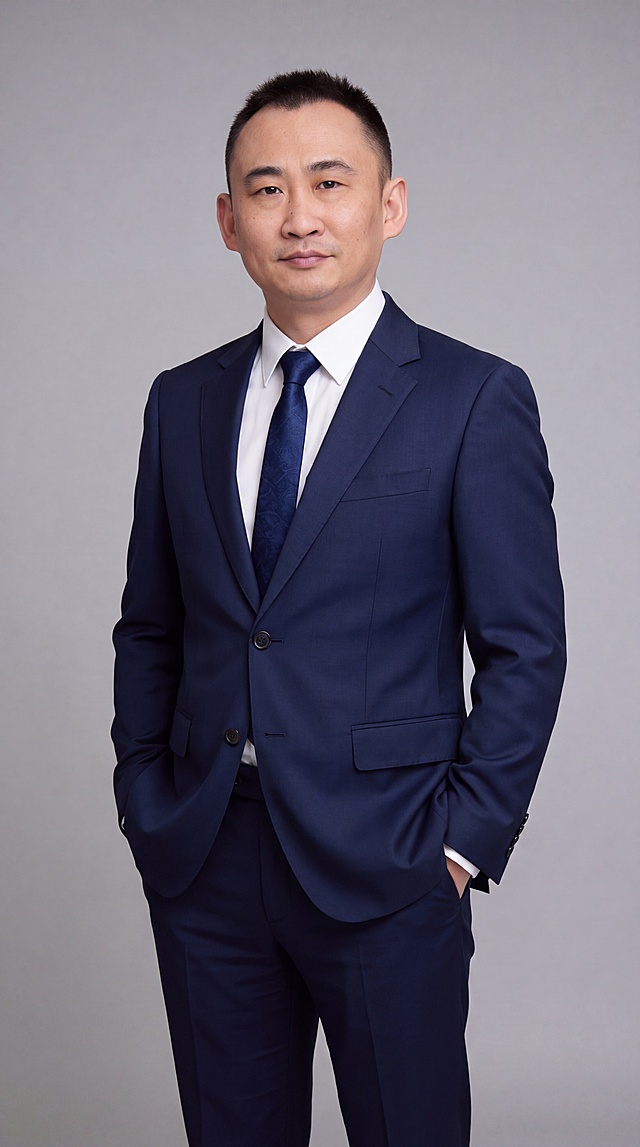 基于参考图中的男性本人形象，生成一张40岁男性商务形象照，全身到小腿位置，高度还原本人面部特征，保留真实皮肤细节与纹理，身穿藏青色西服套装，内搭白色衬衫和深蓝色领带，双手插兜姿势，气质成熟干练，专业商务形象照风格，光线柔和均匀，灰色背景简洁大气，超高清质感，细节丰富