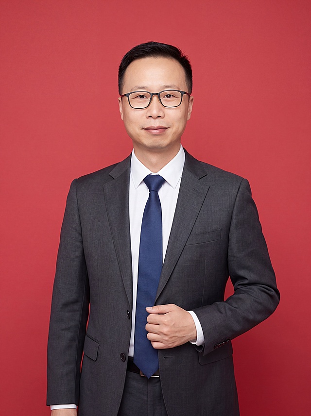 参考图中保留人物脸型、发型、年龄、眼镜等特征生成金融法律专业人士职场形象照,标准焦段50mm,f/4光圈(f/2.8-f/4区间),平视视角(镜头与人物视线齐平);人物占画面70%,人物居中(居中构图),位于画面中心,为视觉聚焦点,入境范围头部及以下至臀部下方10cm(半身像);左右留少量背景空间;头部与画面顶部保留5%空间;头部发型完整,头肩比例协调,人物结构准确;身穿深灰色精纺羊毛混纺西装外套,(平驳领设计,面料呈细腻微微哑光质感);内搭高支精梳棉白色衬衫;下装深灰色精纺羊毛混纺西裤;系深蓝色真丝领带;着装正式干练;严谨理性、专业稳重、公信力强;身形匀称,姿态端正,身体挺拔。呈自然站姿,右手轻握西装前襟,肢体放松且自信;佩戴黑框眼镜;发质微微柔顺,微微蓬松。简约正红色纯色背景(呈现均匀柔和质感),背景光线均匀柔和,强化色彩对比的高级感,极简干净;画质超高分辨率、细节清晰,现代精致感风格;肤质精细化处理;眼神直视镜头,目光坚定且澄澈,表情自然。嘴角上扬;肤质自然细腻,肤色健康均匀,皮肤状态清爽干净,保留真实皮肤细节。正面柔光补光,4800K中性光,面部光比1:1.5。中近景写实摄影,对焦清晰,面部雾面柔光,轻透裸肌感,高清保留皮肤细节。分辨率4K,去除人物之外的所有元素。严格按照图片内容生成。画面比例3:4