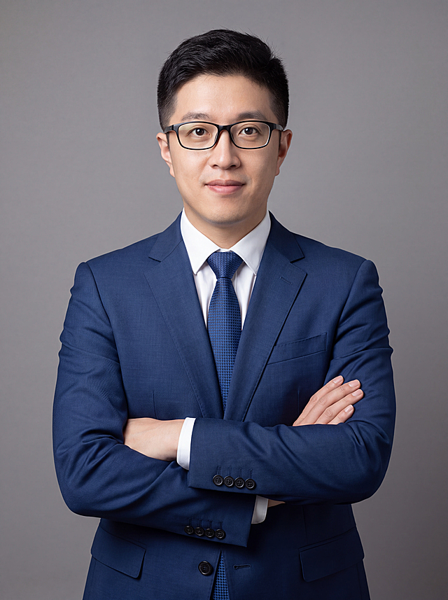 参考图中人物的脸型、五官、年龄、发型、眼镜特征保持不变，生成保险行业专业职业形象照。标准焦段50mm，f/4光圈，平视视角，镜头与人物视线齐平；人物占画面70%，人物居中，位于画面中心，为视觉聚焦点，半身照，左右留少量背景空间；头部与画面顶部保留5%空间；头肩比例协调，人物结构准确。身穿深蓝色精纺羊毛混纺西装外套，平驳领设计，面料呈细腻微微哑光质感；内搭白色高支精梳棉衬衫，系深蓝色几何图案领带；下装深蓝色精纺羊毛混纺西裤；着装正式干练，专业稳重，亲和可信，身形匀称，姿态端正，身体挺拔。呈自然站姿，双手抱胸，肢体放松且自信；佩戴眼镜。发梢微微修整，干练大气，主体锐利。简约中性灰纯色背景，呈现均匀柔和质感，背景光线均匀柔和，强化色彩对比的高级感，极简干净。画质超高分辨率、细节清晰，现代精致感风格；肤质精细化处理；眼神直视镜头，目光坚定且澄澈，表情自然，嘴角微微上扬，亲和友善。肤质自然细腻，肤色健康均匀，哑光肤质清爽干净，保留真实皮肤细节；杰作，最佳画质，超高细节，写实摄影，中近景人像，皮肤质感自然清晰，柔光，正面补光，画面干净清新，高清皮肤细节；面部光比1:1.5，4800K中性光，微微修饰脸型，肤质哑光细腻，面部雾面柔光，轻透裸肌感，真实毛孔纹理。画面比例3:4