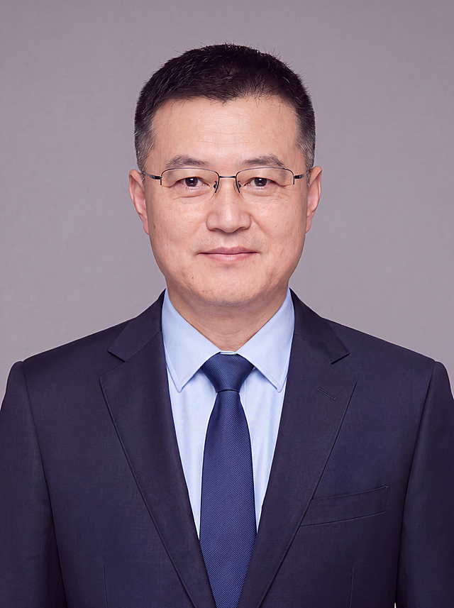 参考图中保留人物脸型、发型、年龄、眼镜等全部特征生成企业高管商务大头照,标准焦段50mm,f/4光圈(f/2.8-f/4区间),平视视角(镜头与人物视线齐平);人物占画面85%,人物居中(居中构图),位于画面中心,为视觉聚焦点,入境范围头部及肩部(紧凑大头照,仅保留头肩部分);左右留极少量背景空间;头部与画面顶部保留3%空间;头部发型完整,头肩比例协调,人物结构准确;身穿藏青色精纺羊毛混纺定制西装外套,(平驳领设计,面料呈细腻微微哑光质感);内搭浅蓝色高支精梳棉衬衫;系深蓝色条纹真丝领带;着装正式干练;权威沉稳、格局开阔、从容果决、值得信赖;身形匀称,姿态端正,身体挺拔。呈自然站姿,肩部端正,肢体放松且自信;佩戴精致商务无框眼镜;发质微微柔顺,微微蓬松。简约中性灰色纯色背景(呈现均匀柔和质感),背景光线均匀柔和,强化色彩对比的高级感,极简干净;画质超高分辨率、细节清晰,现代精致感风格;肤质精细化处理;眼神直视镜头,目光坚定且澄澈,表情自然。嘴角上扬;肤质自然细腻,肤色健康均匀,皮肤状态清爽干净,保留真实皮肤细节。正面柔光补光,4800K中性光,面部光比1:1.5。中近景写实摄影,对焦清晰,面部雾面柔光,轻透裸肌感,高清保留皮肤细节。分辨率4K,去除人物之外的所有元素。严格按照图片内容生成。画面比例3:4