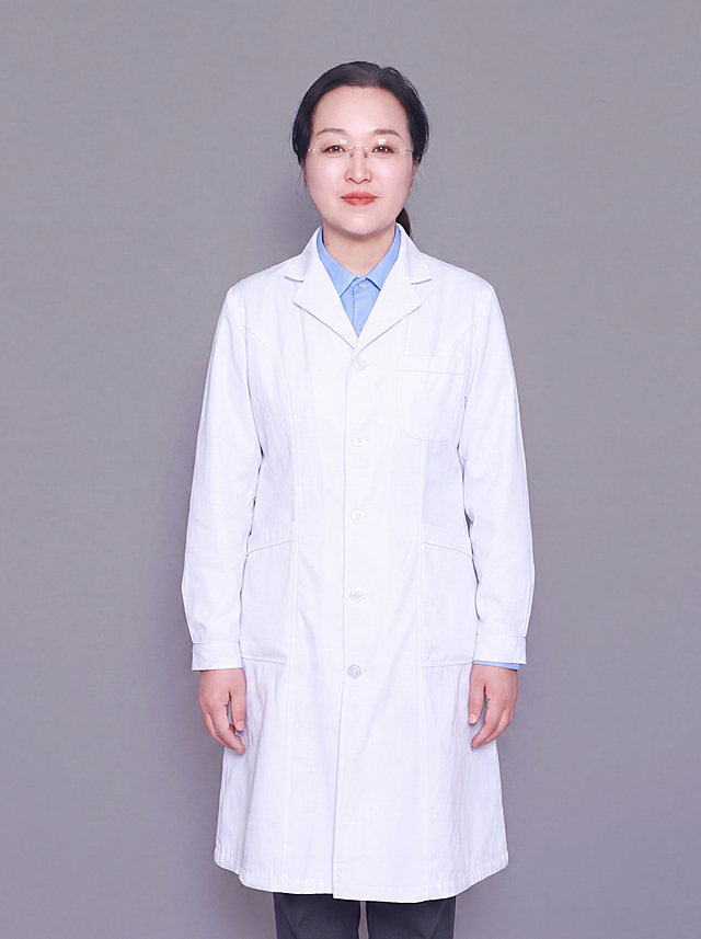参考图中保留人物脸型、发型、年龄、五官、眼镜等所有面部特征生成医生职业形象照，人物身体正面朝向镜头，标准焦段50mm，f/4光圈，平视视角，镜头与人物视线齐平；人物占画面70%，人物居中构图，位于画面中心，为视觉聚焦点，入境范围头部及以下至小腿中部，左右留少量背景空间；头部与画面顶部保留5%空间；头部发型完整，头肩比例协调，人物结构准确；身穿整洁白色白大褂，内搭浅蓝色翻领衬衫，下装深灰色西裤；着装正式干练，专业仁心、沉稳可靠、温和严谨；身形匀称，姿态端正，身体挺拔。呈正面站姿，双手自然下垂于身体两侧，肢体放松且自信；佩戴无框眼镜；发质微微柔顺，微微蓬松。简约微微中度灰色纯色背景，呈现均匀柔和质感，背景光线均匀柔和，强化色彩对比的高级感，极简干净；画质超高分辨率、细节清晰，现代精致感风格；肤质精细化处理；眼神直视镜头，目光坚定且澄澈，表情自然，嘴角上扬；清透自然裸妆，轻薄底妆加淡唇妆，妆感轻薄轻透裸肌感，通透感肤质，肤质自然细腻，肤色健康均匀，雾面柔光裸肌感，保留真实皮肤细节。正面柔光补光，4800K中性光，面部光比1:1.5，色调明亮。中近景写实摄影，对焦清晰，高清保留皮肤细节。分辨率4K，去除人物之外的所有元素，严格按照图片内容生成，画面比例3:4