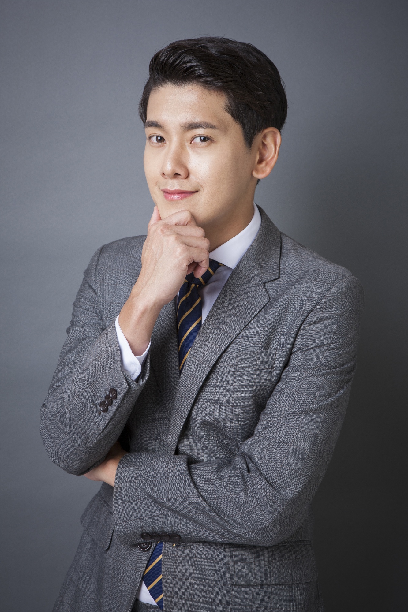 年轻的自信微笑的商务男士，穿着灰色西装，目不转睛地盯着前面。Young confident smiling business man in ...