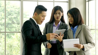 办公室工作人员手持文件夹中的文档，并在办公室中使用数字平板电脑。