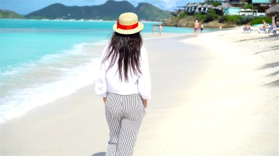 热带海滨的年轻美女。快乐的女孩背景加勒比岛上蓝天碧绿的海水
