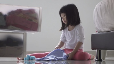 帮助做家务的女孩。把衣服折叠起来放在抽屉的柜子里。