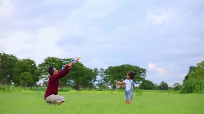 亚洲小孩女孩和父亲带着风筝在自然界的草地上奔跑和快乐，慢动作