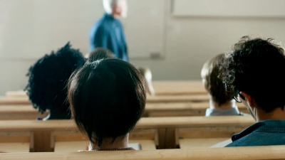 背看学生在教室里听著名教授朗读讲座。聪明的年轻人在大学学习。