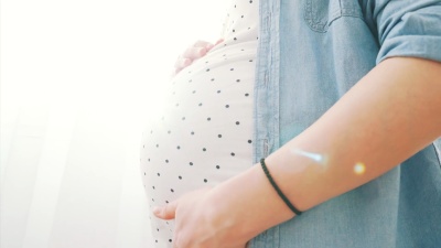 在阳光明媚的日子里，孕妇腹部的特写镜头。