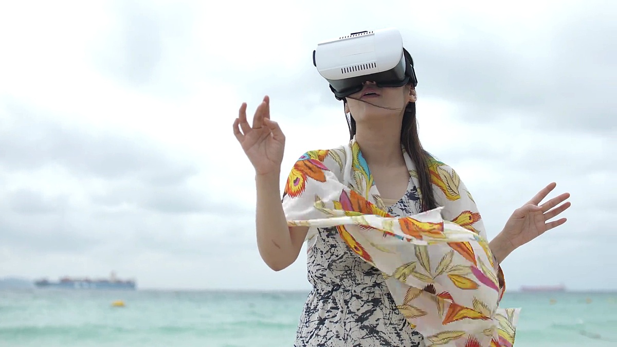 使用3D虚拟现实的年轻亚洲女性在沙滩上搜索，慢动作