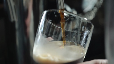 酒保把黑啤酒倒在玻璃杯里。