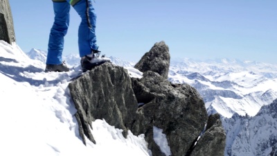 登山者在阳光明媚的日子里用冰斧到达雪山顶。登山滑雪活动。滑雪者人们在高山户外进行冬季雪上运动。后视图。慢速运动60p  视频