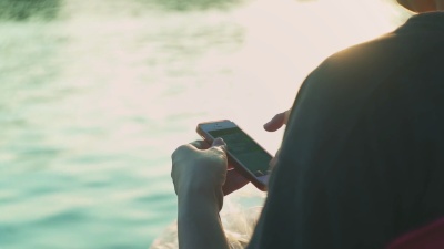 日落时分在公园使用智能手机的女人，慢动作