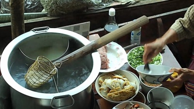 在水上市场的船上烹调泰国面条