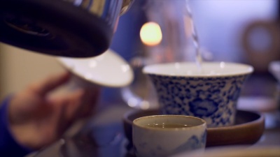 男性双手将热水倒入碗中泡茶。男人手拿茶杯