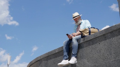 留胡子的老人在城市里抽电子烟