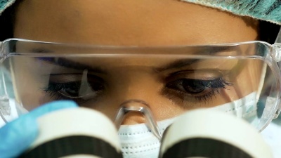 迷人的女科学家在显微镜下研究微生物，特写