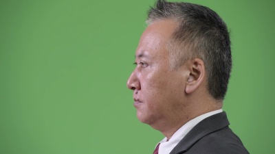 绿色背景下成熟日本商人的侧面视图