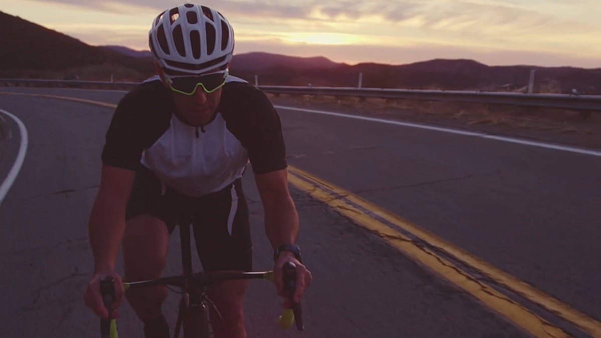 日落时分慢动作戏剧性健身男子在公路自行车上山锻炼