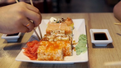 朋友在日本餐厅吃寿司卷，寿司吧。晚餐