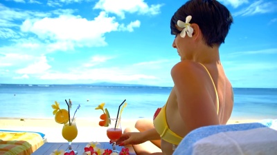 女士在海滩上用鸡尾酒放松