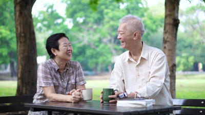 亚洲老年退休夫妇在公园喝咖啡看书