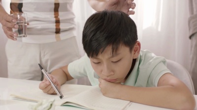 亚裔父亲站在那里听着沮丧的儿子模糊了家庭作业