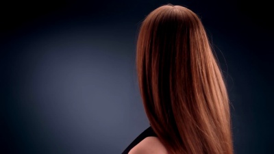 美丽的深色金发女人甩着长发。看着相机