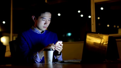 男性高管在办公室办公桌前使用手机 