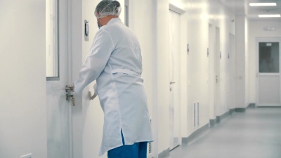 穿着防护服的工人关闭了医院走廊的一扇门
