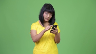 美丽快乐的亚洲女人一边打电话一边惊讶