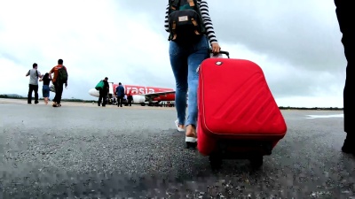 带着红色行李走上飞机的女性旅行者