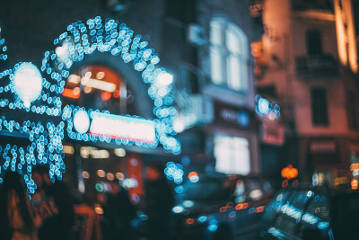 朦胧的城市在夜晚。散景。美丽的抽象背景与散焦的建筑，汽车，城市灯光，人。丰富多彩的散景背景与城市夜景