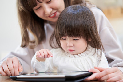 一个亚洲女孩和妈妈一起看平板电脑