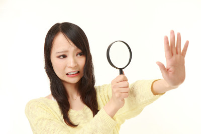 一个震惊的年轻女子透过放大镜看她的指甲