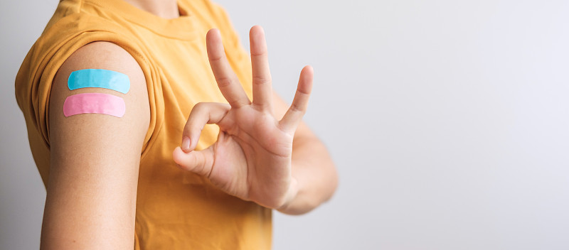一名妇女在接种了covid - 19疫苗后用绷带显示OK迹象。疫苗接种、群体免疫、副作用、加强剂、疫