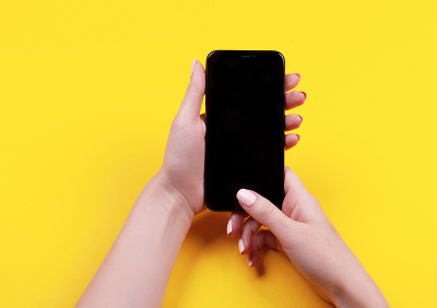 一个女人的手在黄色背景使用手机俯视图。