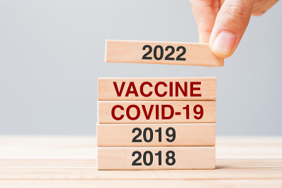 桌子背景上，手拉着2022块疫苗、COVID-19和2019木制建筑。危机经济、疫苗接种、免疫和冠状
