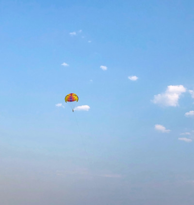 低角度的人滑翔伞在海上对蓝色的天空
