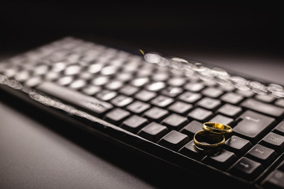 不忠或实质上的背叛。个人电脑键盘上的金婚戒。