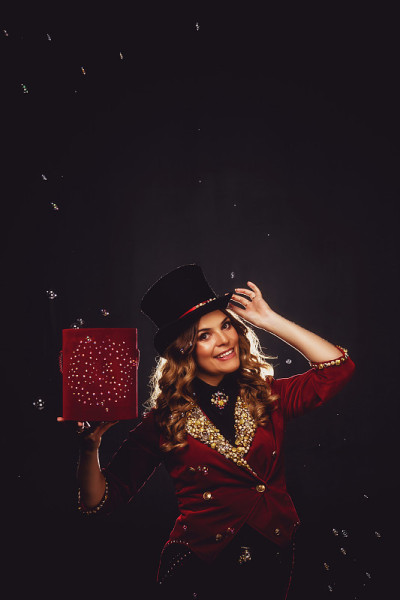 女魔术师用肥皂泡表演，一个穿着戏剧服装的魔术师，在黑色的背景上
